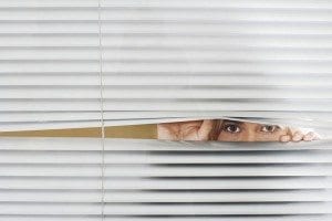 Woman looking through venetian blinds