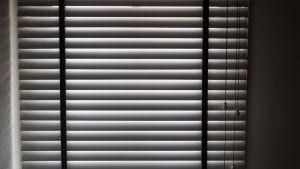 View of Venetian blinds closed from inside with sunlight glaring on other side.