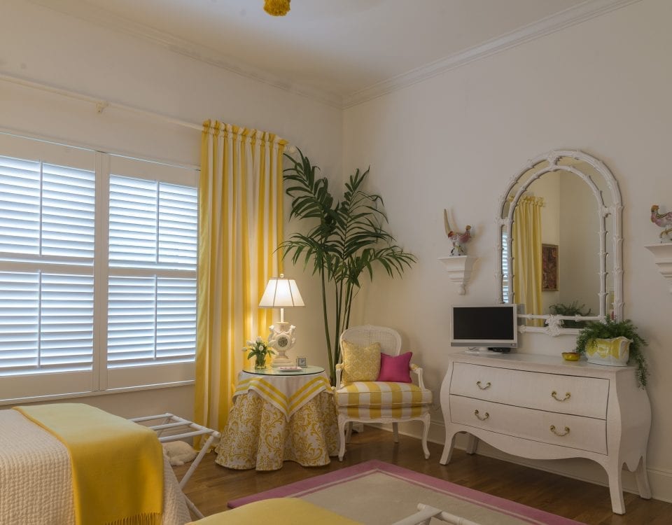 yellow-themed bedroom with white shutters and green corner plant
