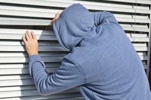 Suspicious man looking through PVC blinds of window