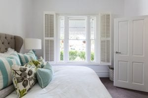 Bedroom window with a garden view through timber shutters.